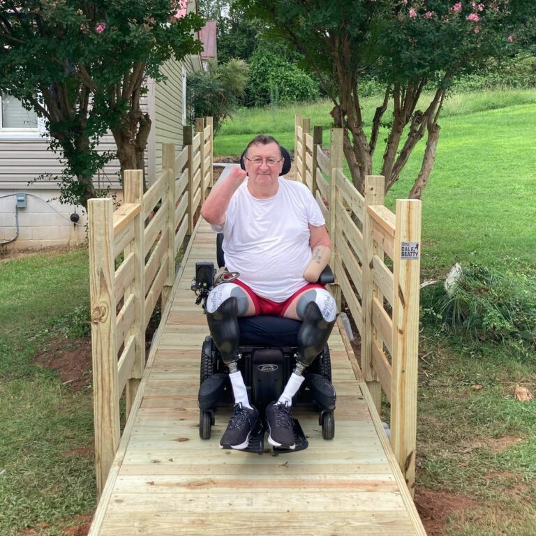 Veteran R. Canterbury in wheelchair on Purple Heart Homes built ramp.